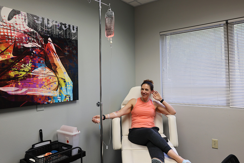 woman sitting in colorful clinic receiving vitamin drips IV